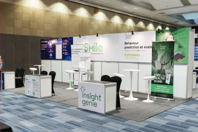 Mid-sized booth setup with carpeted floor, backdrop, counter, chairs, and branded panels