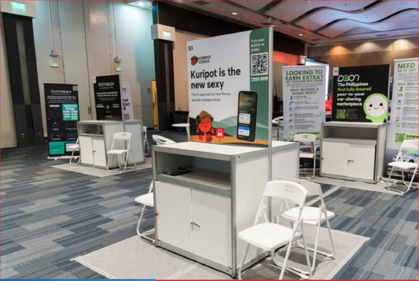Small booth setup with counters, printed backdrops, chairs, and product signage